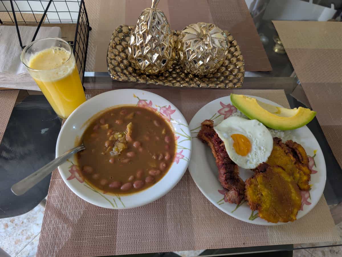 Bandeja paisa uvařená doma: fazole, vejce, chicharrón, plátano, avokádo.