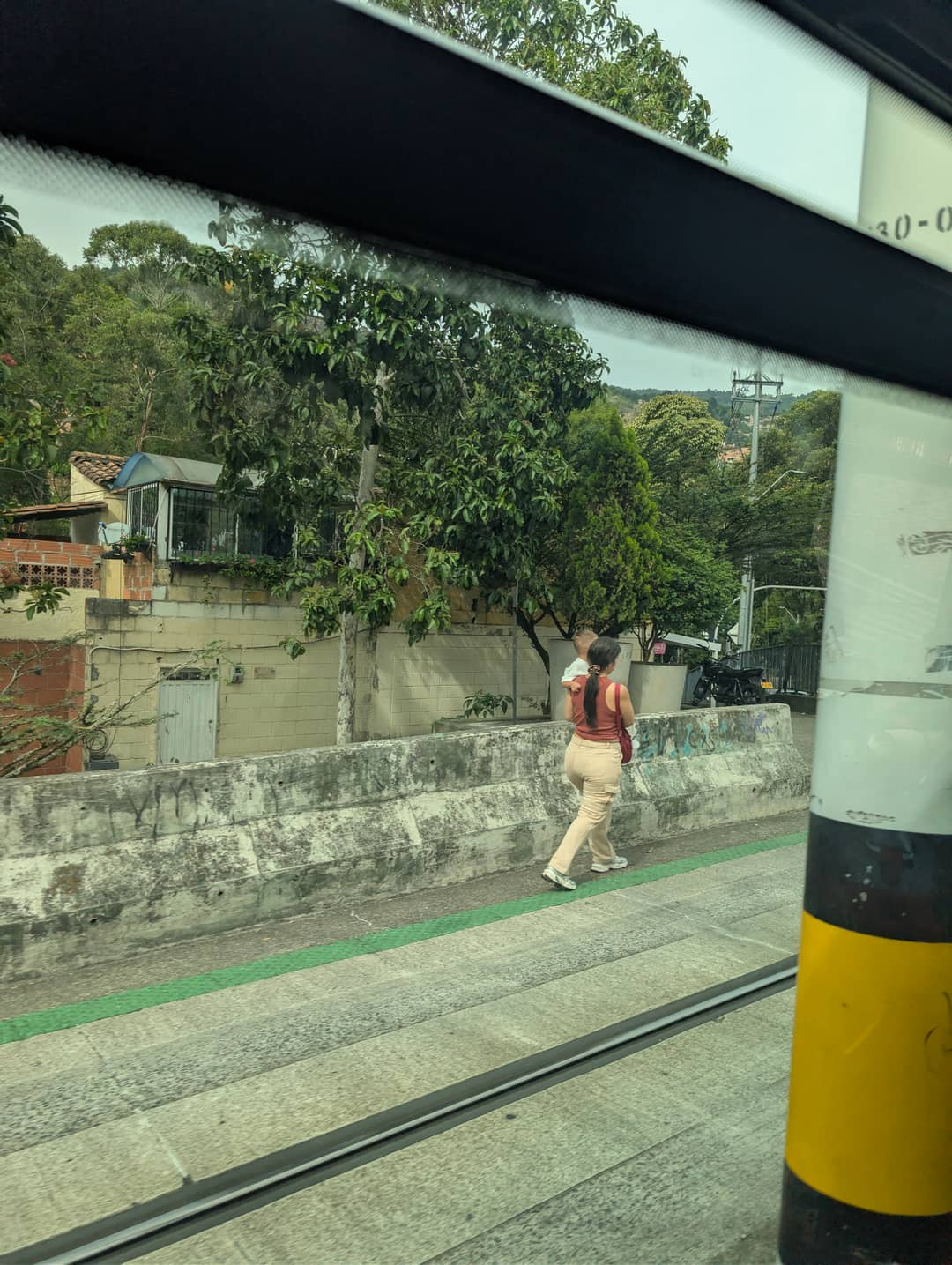 From the tram window: a wall, the track and a pedestrian.