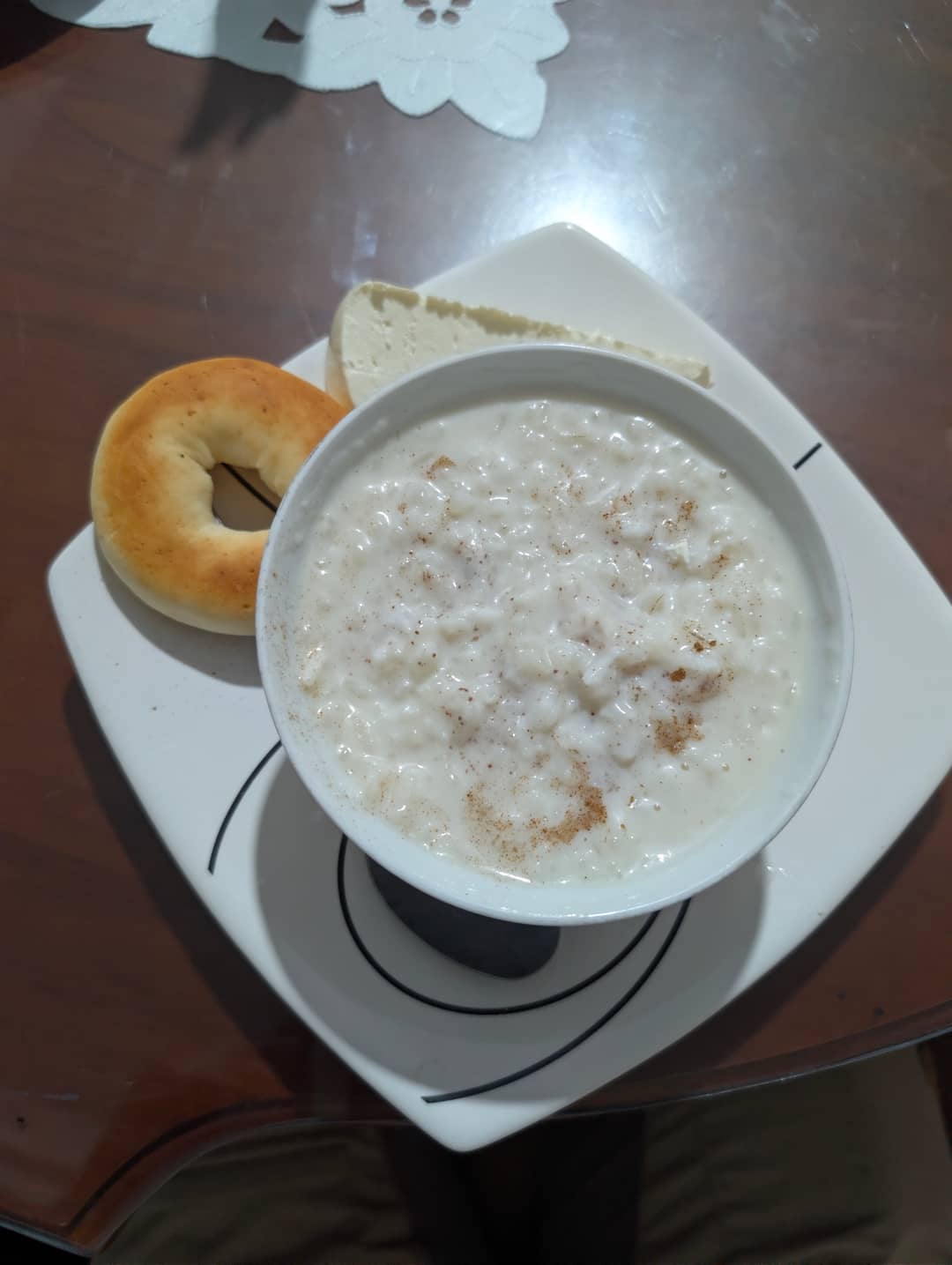 Arroz con leche podávaná horká, s pečivem a plátkem quesita.
