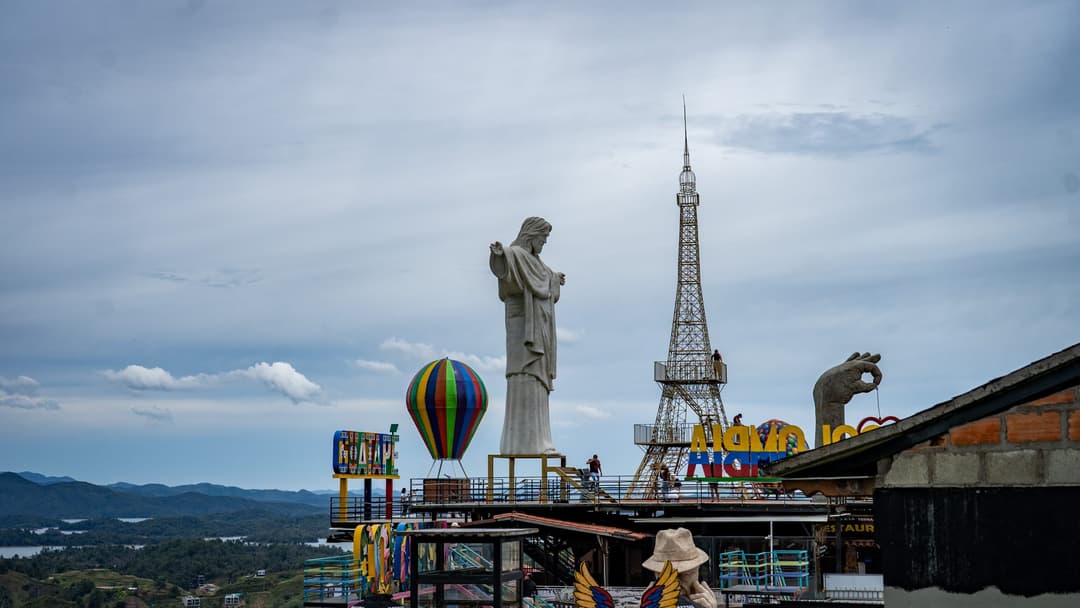 An Eiffel tower made of tubes and a giant statue below the rock.